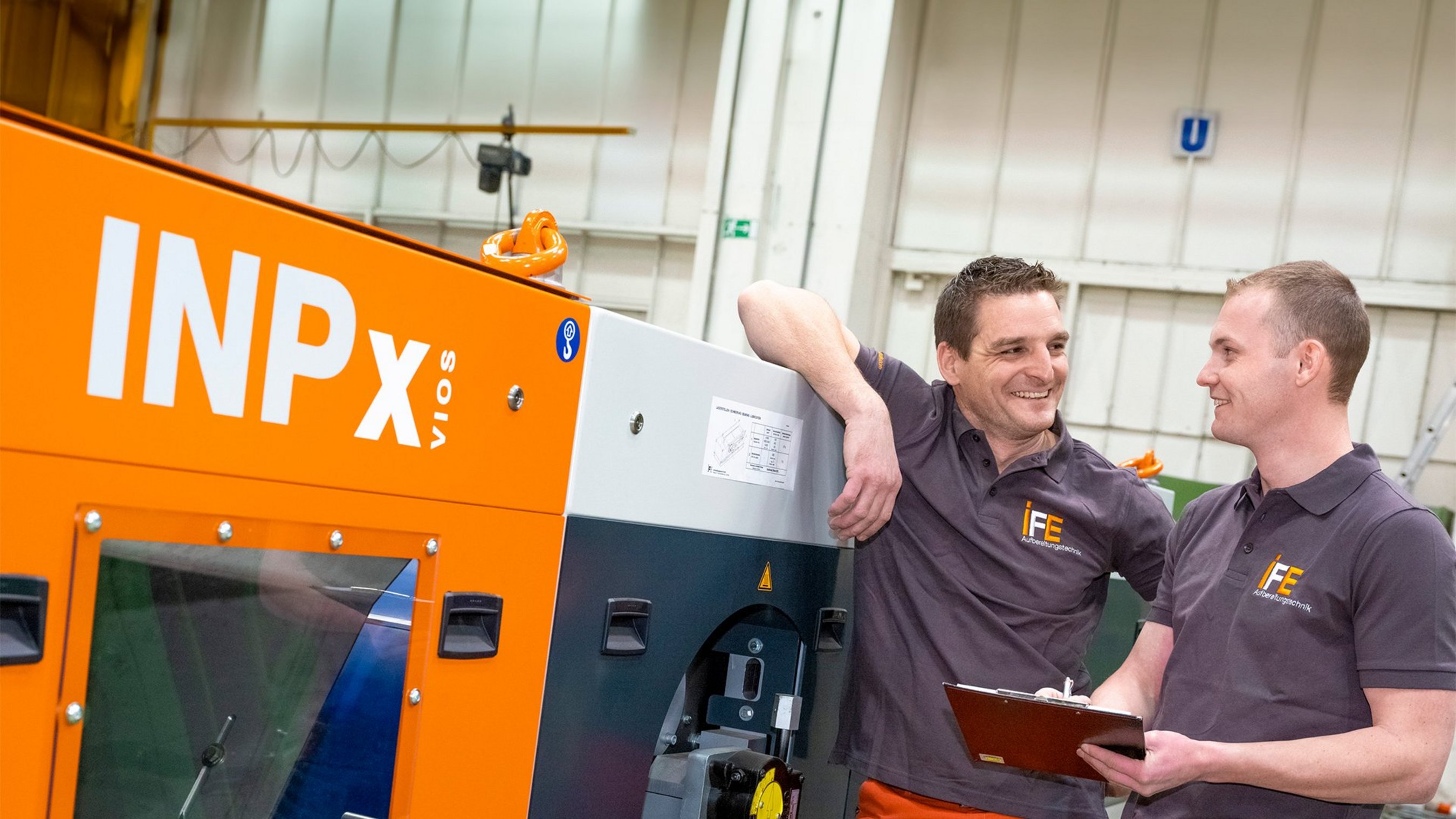 IFE Mitarbeiter unterhalten sich neben einem IFE Wirbelstromscheider in der Produktion.